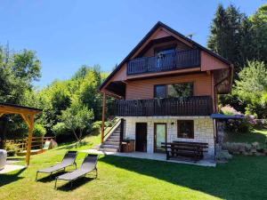 a house with a deck and two chairs in the yard at Chalet Zasavka in Dol pri Hrastniku