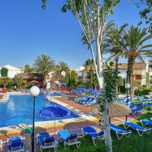 a swimming pool with blue chairs and palm trees at Veracoast 133 in Los Amarguillos