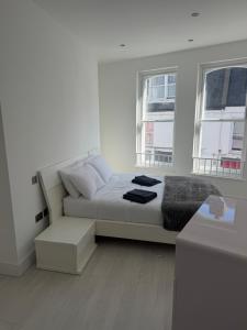 a white room with a bed and two windows at 1 bedroom flat in Saint Helier Jersey