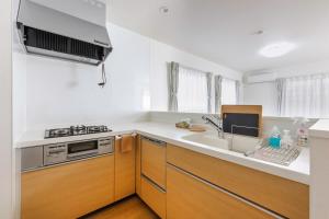 a white kitchen with a sink and a stove at Asobi Stay大日 山吹 in Nagoya