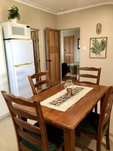 a kitchen with a wooden table with chairs and a refrigerator at Jack's Tidal Pool Shack in Kingscote +14 photos