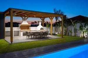 a patio with a table and chairs next to a swimming pool at Villa Elesia in Kremasti
