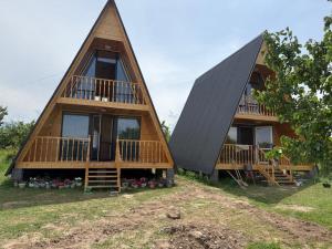 two thatched cottages with decks on the grass at JEEK A-Frame in Tong