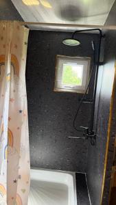 a small bathroom with a window and a shower curtain at JEEK A-Frame in Tong +7 photos