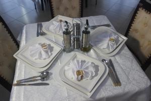 a table with two white plates and napkins on it at Astória - Hotel & Suites in Soyo