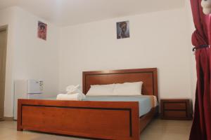 a bed with a wooden headboard in a bedroom at Astória - Hotel & Suites in Soyo