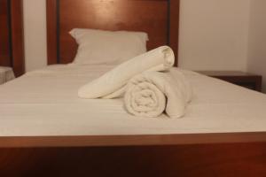 a pile of towels sitting on a bed at Astória - Hotel & Suites in Soyo +8 photos