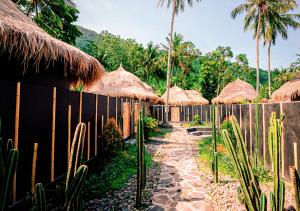 a fence with straw umbrellas and a path with plants at Lombok Souls in Senggigi
