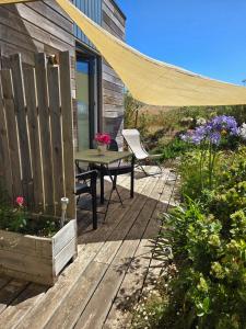 a patio with a table and a chair on a deck at Chambre privée proche plages in Plozévet