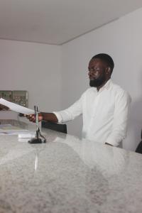 a man is standing at a counter with a machine at Astória - Hotel & Suites in Soyo