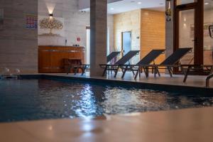 a swimming pool with chairs and a table and water at Moj Hir Boutique Rooms & Wellness Spa in Jastrebarsko