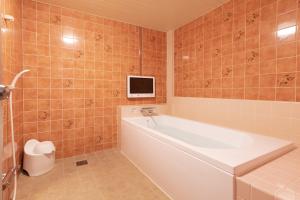 a bathroom with a tub and a tv on the wall at Earn Exception in Isesaki