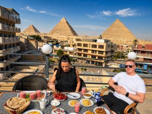 a man and woman sitting at a table in front of the pyramids at Red pyramids view hotels in Cairo