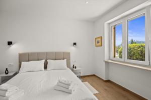 a white bedroom with a large bed and a window at Danijela Holiday Home in Labin