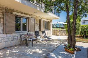 a patio with chairs and a table and a tree at Danijela Holiday Home in Labin