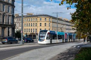 a white and blue tram on a city street at Edinburgh Central Accommodation in Edinburgh