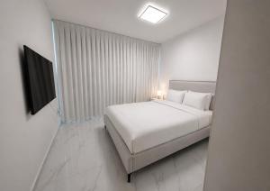 a white bedroom with a bed and a television at ODAR suite in Caesarea