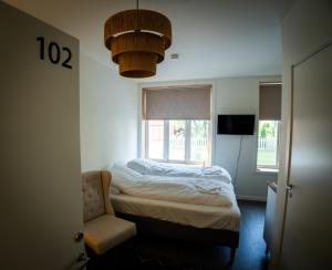 ein Schlafzimmer mit einem Bett, einem Stuhl und einem Fenster in der Unterkunft Centrumrooms in Mosjøen