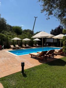 a swimming pool with chairs and umbrellas next to it at Aparthotel Borsh in Borsh