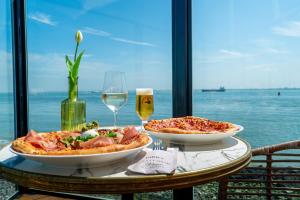 a table with two pizzas and a glass of wine at Punt al Mare in Vlissingen