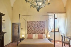 a bedroom with a canopy bed and a chandelier at Casa Becci Central Large & Sunlit Historical Flat in San Gimignano