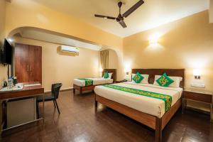 a hotel room with two beds and a desk at Treebo Sunshine Beach Resort with Swimming Pool in Calangute +32 photos