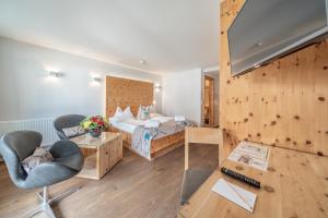 a hotel room with a bed and a desk and chairs at Naudererhof - 4-Stern-Superior in Nauders