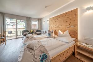 a bedroom with a large bed with a wooden headboard at Naudererhof - 4-Stern-Superior in Nauders
