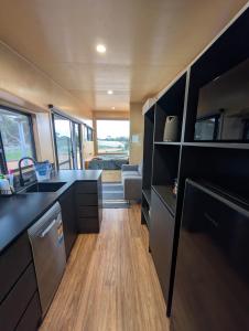 a kitchen with black cabinets and a sink at Nine77 - Tiny Home Retreat in Esperance
