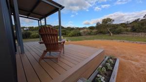 a wooden rocking chair sitting on a porch of a house at Nine77 - Tiny Home Retreat in Esperance