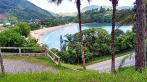 a view of a beach from a hill with palm trees at Ubatuba's Surf hotel in Ubatuba