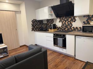a kitchen with white cabinets and a living room at Appartement avec jacuzzi in Chalon-sur-Saône