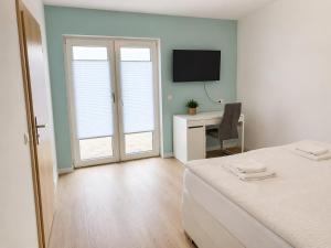 a bedroom with a bed and a desk with a television at Zimmer-Vermietung an der Ostsee, neben der Median-Klinik in Wismar