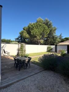 a wooden deck with a table and chairs on it at Lou Cigalou Clim, jardin privé, parking & Wi-Fi 1 à 4 pers in Avignon