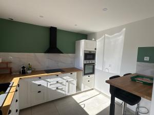 a kitchen with white cabinets and green walls at Lou Cigalou Clim, jardin privé, parking & Wi-Fi 1 à 4 pers in Avignon