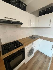 a kitchen with white cabinets and a stove and a sink at T3 proche musées et panorama in Château-Chinon