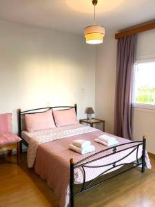 ein Schlafzimmer mit einem Bett mit rosa Kissen und einem Fenster in der Unterkunft Aethera Maisonette in Kokóni