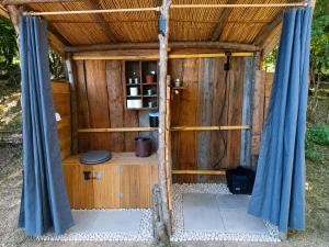 a wooden outhouse with a door and blue curtains at Le nid de bois insolite in Haget +3 photos