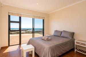 a bedroom with a bed and a view of the ocean at High Tide Seafront at Franskraal in Franskraalstrand