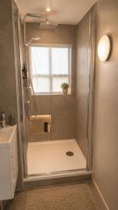 a shower stall in a bathroom with a window at Grindavik Guesthouse self check in & out in Grindavík