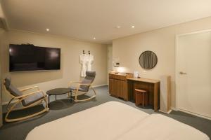 a hotel room with a bed and chairs and a tv at Anook Hotel Suwon Ingye in Suwon