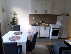a small kitchen with a table and a white table and chairs at Apartman Angela in Foča