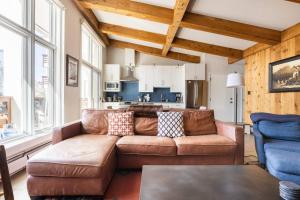 a living room with a brown couch and a kitchen at Mountainside Top Floor Condo - Treetops Lionshead in Vail