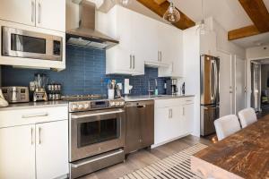 a kitchen with white cabinets and stainless steel appliances at Mountainside Top Floor Condo - Treetops Lionshead in Vail