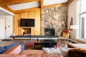 a living room with a stone fireplace and a tv at Mountainside Top Floor Condo - Treetops Lionshead in Vail +29 photos