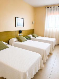 a hotel room with three beds in a room at Hostal la Abuela in Simancas