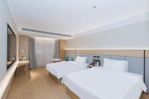 a hotel room with two beds and a television at JI Hotel Beijing Xizhimen in Beijing