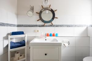 a white bathroom with a sink and a mirror at Hotel & Ferienunterkünfte Hus Seeblick in Fehmarn +125 photos