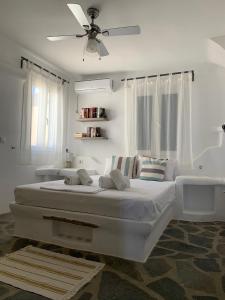a white bedroom with a bed with a ceiling fan at The Sunrise Villa in Koumáros