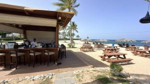 a bar on the beach with tables and chairs at Navy Studio By Bait Zain in As Sīfah